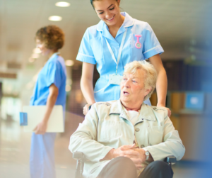 An older woman in a wheelchair is attended by a female nurse