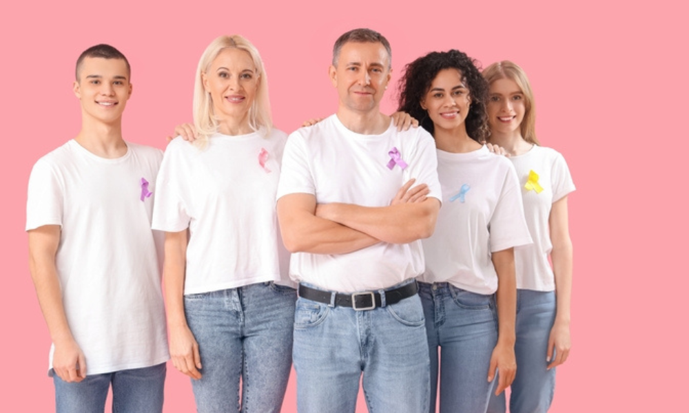 Cancer Awareness Fund A group of people wearing cancer awareness ribbons against a pink background.
